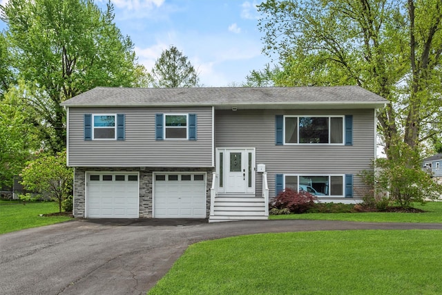 raised ranch featuring stone siding, aphalt driveway, a front lawn, and an attached garage
