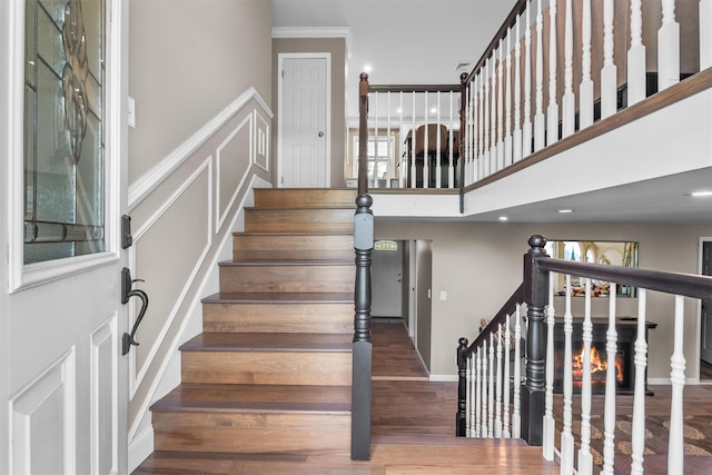 stairs featuring ornamental molding, a high ceiling, baseboards, and wood finished floors