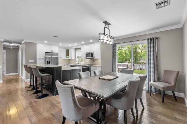 dining space featuring crown molding, baseboards, visible vents, and wood finished floors