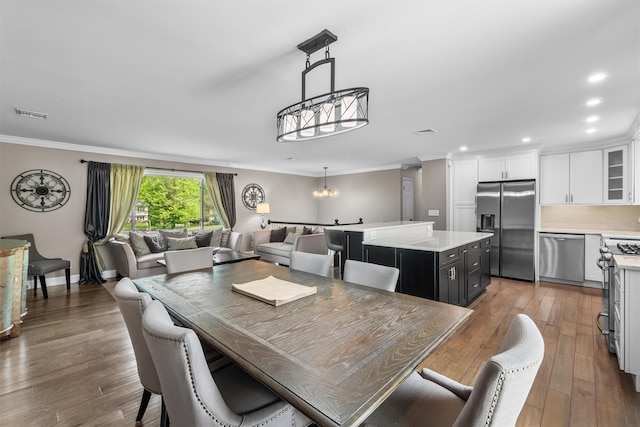 dining space with a notable chandelier, recessed lighting, ornamental molding, visible vents, and wood finished floors