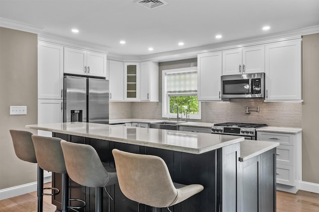 kitchen with baseboards, stainless steel appliances, a center island, and a sink