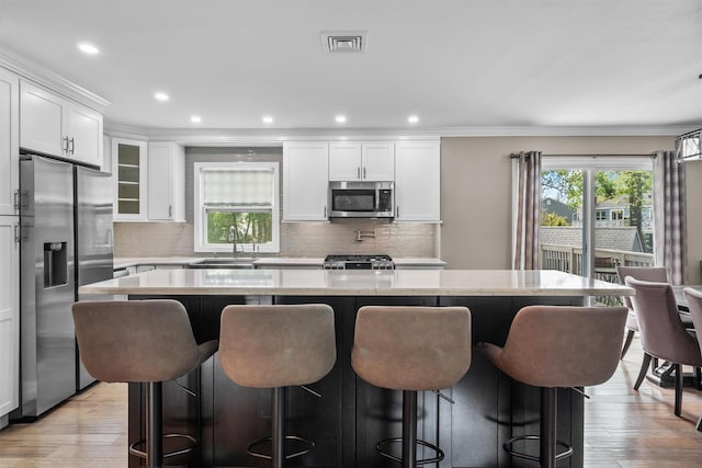 kitchen with visible vents, a sink, a kitchen bar, light wood-style floors, and stainless steel appliances