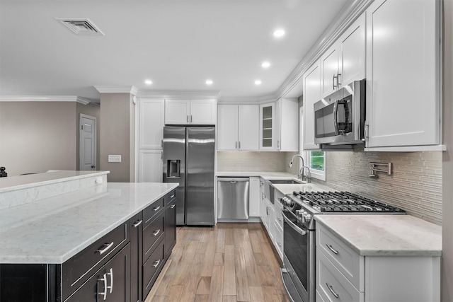 kitchen with crown molding, white cabinetry, stainless steel appliances, and visible vents