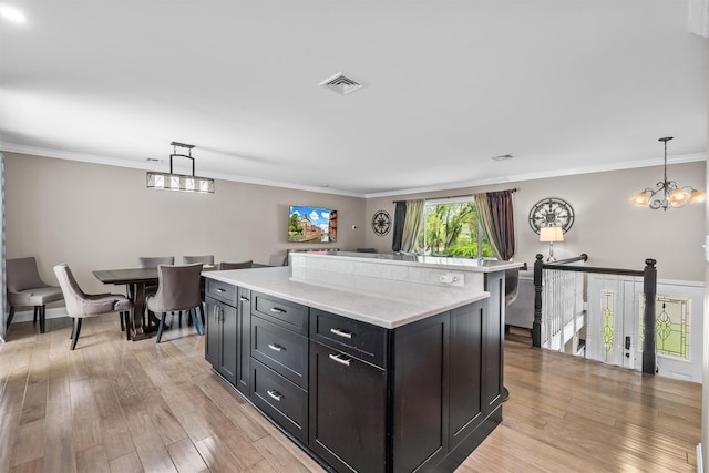 kitchen featuring light wood finished floors, an inviting chandelier, a center island, pendant lighting, and visible vents