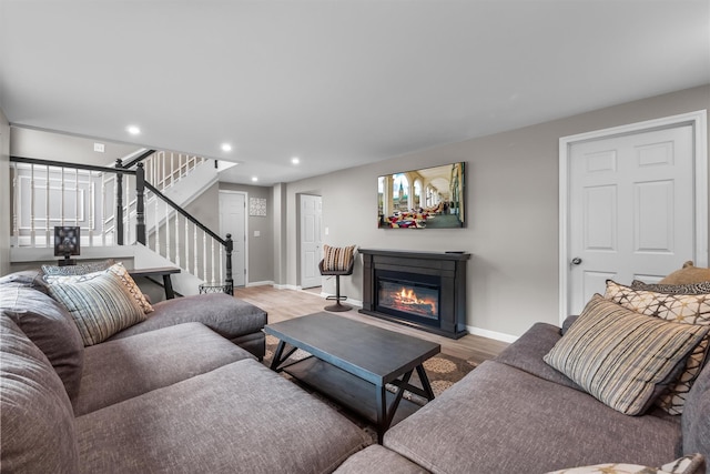 living room with stairway, baseboards, a glass covered fireplace, light wood-style floors, and recessed lighting