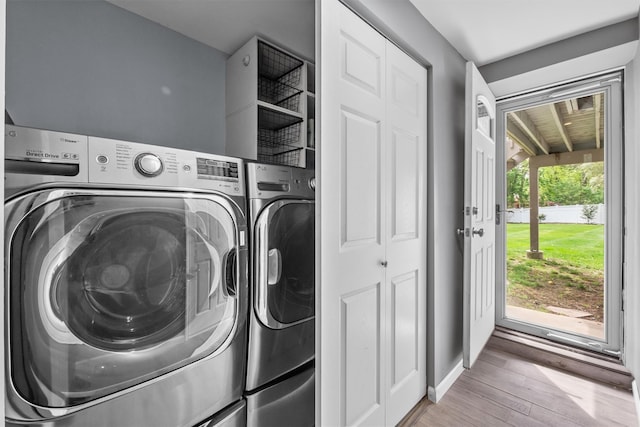 clothes washing area featuring laundry area, independent washer and dryer, and wood finished floors