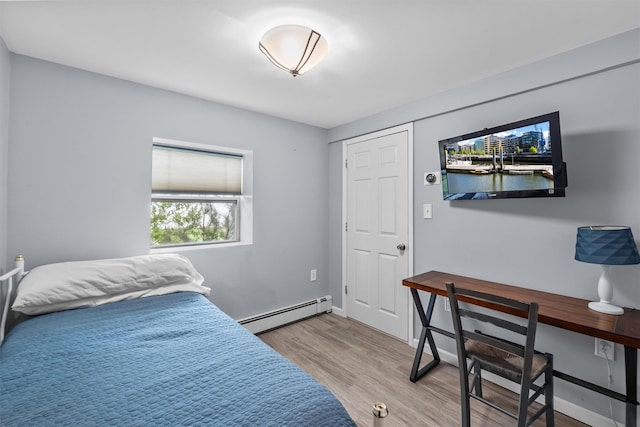 bedroom with baseboards, baseboard heating, and wood finished floors