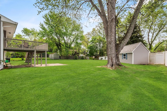 view of yard with a shed, an outbuilding, stairway, a fenced backyard, and a wooden deck