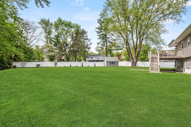 view of yard with stairs, a storage shed, an outdoor structure, a fenced backyard, and a wooden deck