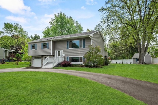 bi-level home with a garage, driveway, fence, and a front yard