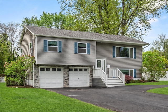 split foyer home featuring roof with shingles, an attached garage, stone siding, driveway, and a front lawn