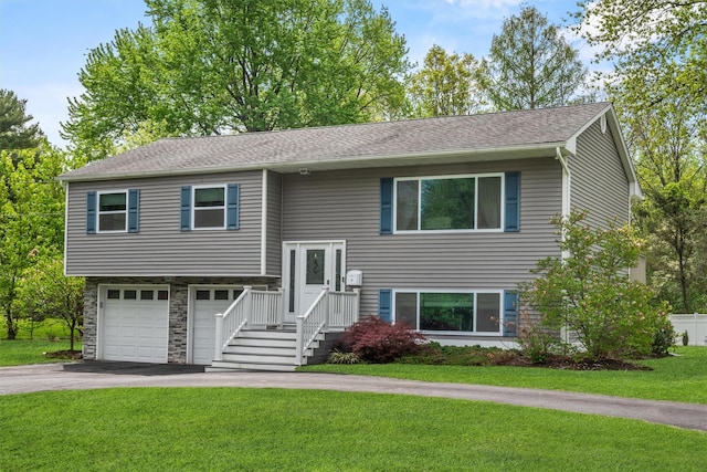 raised ranch featuring aphalt driveway, a garage, stone siding, and a front yard
