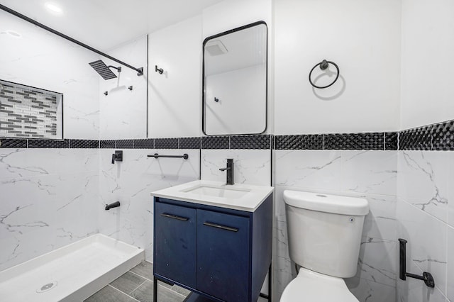 bathroom featuring tile walls, toilet, a shower stall, and vanity