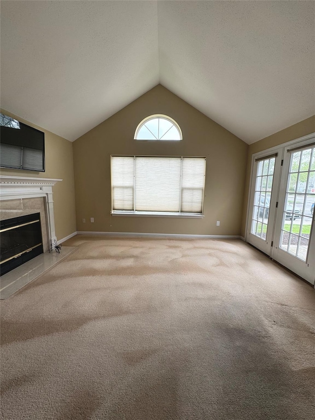 unfurnished living room with carpet flooring, vaulted ceiling, baseboards, and a high end fireplace