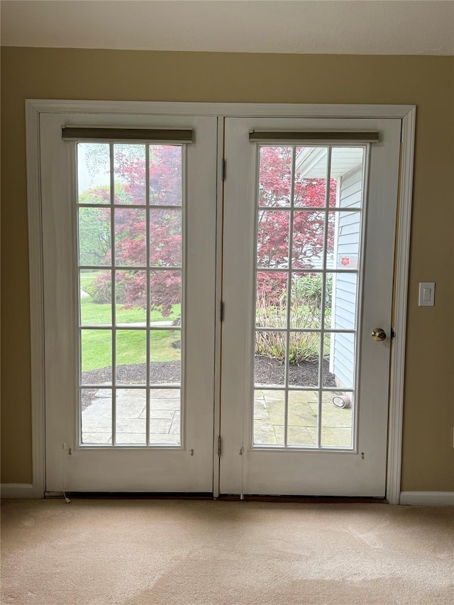 entryway featuring light carpet, plenty of natural light, and baseboards