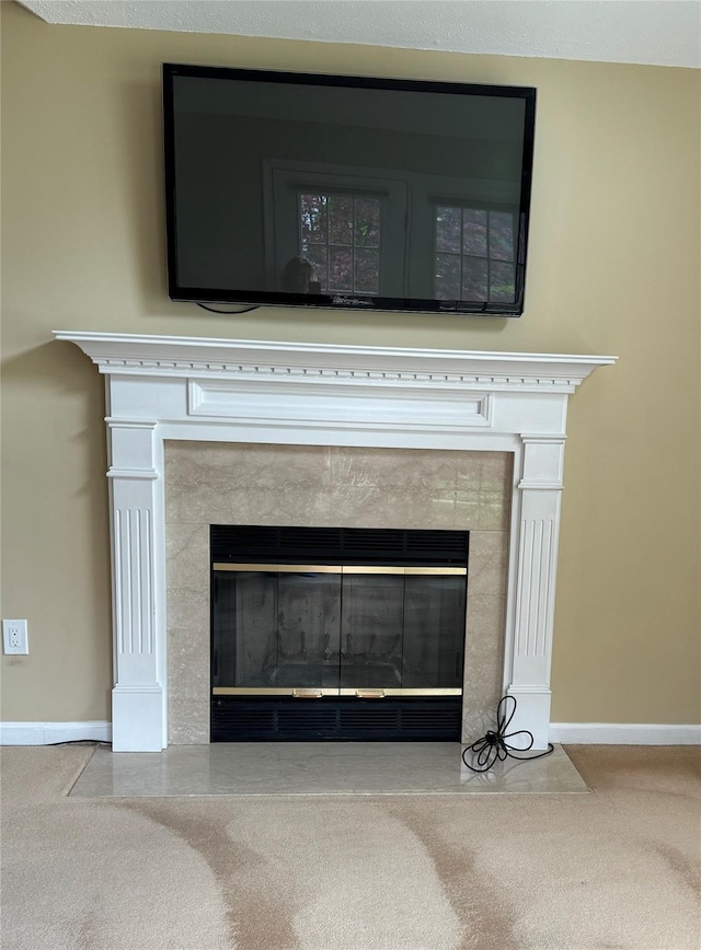 detailed view of a fireplace, baseboards, and carpet flooring