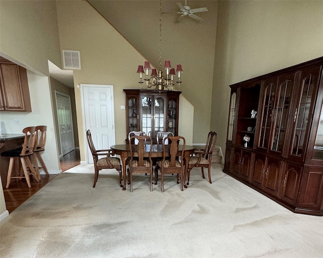 dining room featuring high vaulted ceiling, light carpet, a chandelier, a ceiling fan, and baseboards