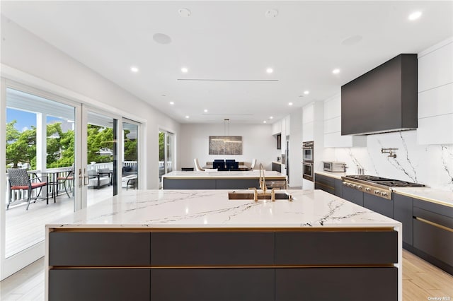 894 S Long Beach Ave, Freeport, NY 11520 - kitchen with a large island with sink, stainless steel gas stovetop, modern cabinets, light wood-type flooring, and recessed lighting