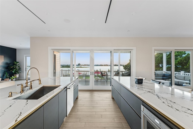 894 S Long Beach Ave, Freeport, NY 11520 - kitchen featuring french doors, light stone counters, gray cabinetry, stainless steel dishwasher, and light wood finished floors