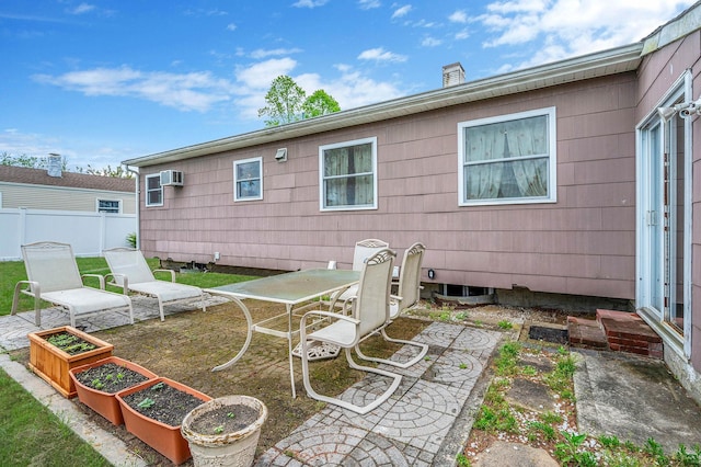 rear view of house featuring fence, a patio, an AC wall unit, and a vegetable garden