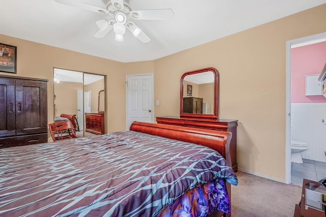 carpeted bedroom with ensuite bathroom and a ceiling fan