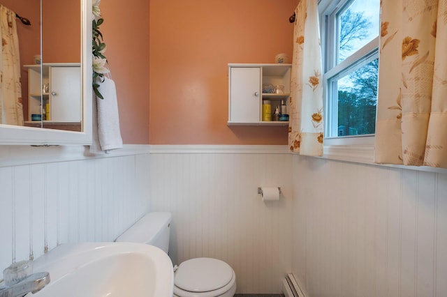 half bathroom featuring wainscoting, toilet, and a sink