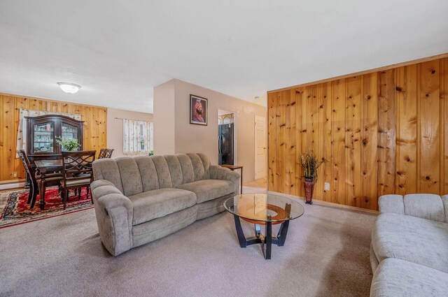 carpeted living area with wood walls
