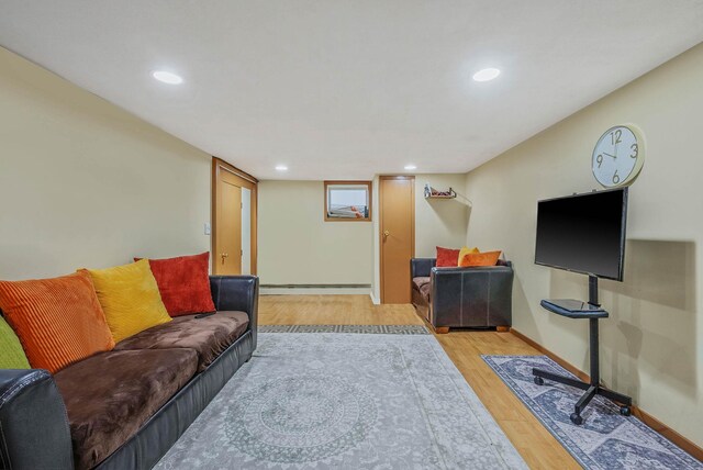 living room featuring light wood-style flooring, recessed lighting, a baseboard heating unit, and baseboards