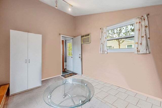 unfurnished bedroom with multiple windows, a wall unit AC, baseboards, and track lighting