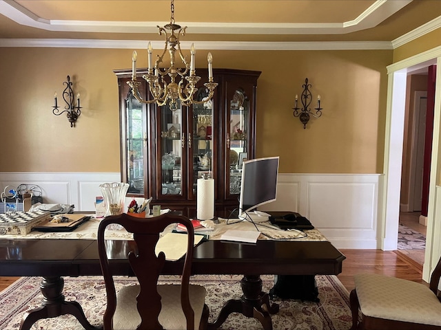 dining room with an inviting chandelier, a raised ceiling, crown molding, and wood finished floors
