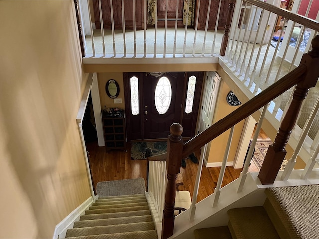 foyer with baseboards, wood finished floors, and stairway