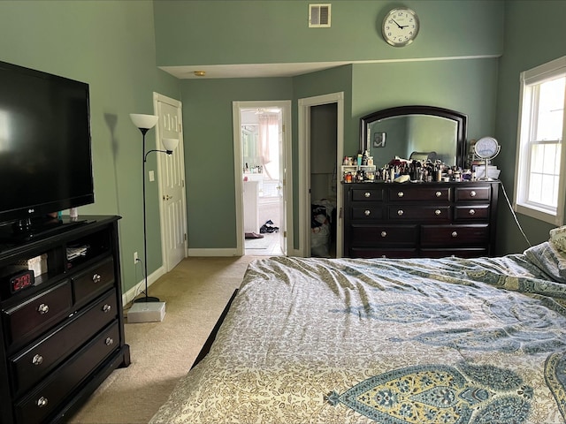 bedroom featuring visible vents, connected bathroom, baseboards, and light colored carpet