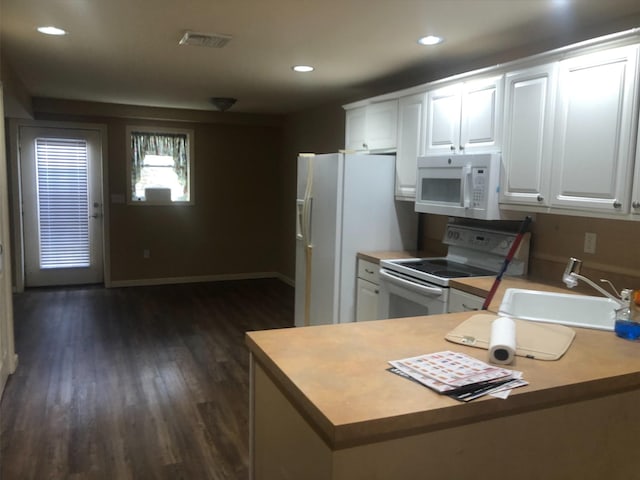 kitchen featuring visible vents, a peninsula, white appliances, white cabinetry, and a sink