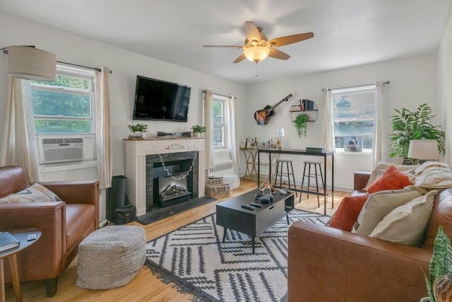living area with ceiling fan, wood finished floors, a fireplace, and a healthy amount of sunlight
