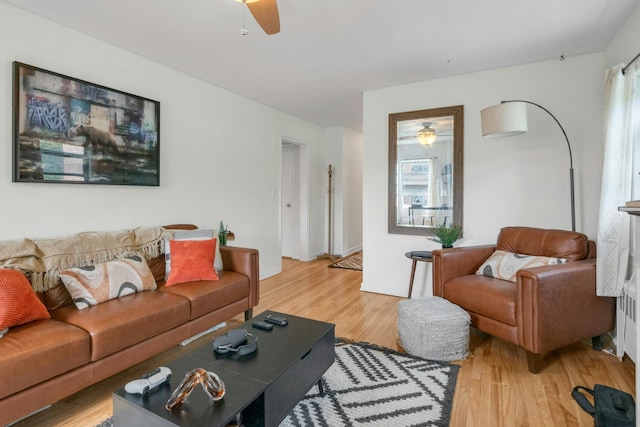 living room with light wood-type flooring, baseboards, and a ceiling fan