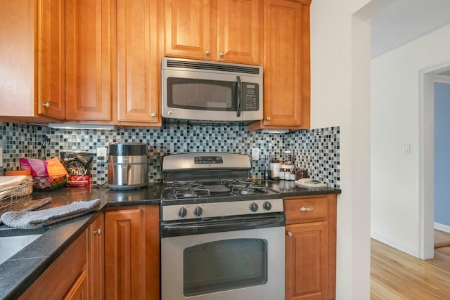 kitchen with appliances with stainless steel finishes, brown cabinetry, tasteful backsplash, and light wood-type flooring