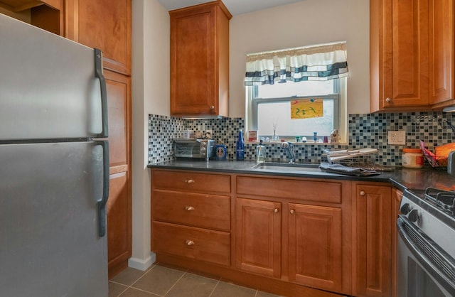 kitchen with freestanding refrigerator, dark countertops, decorative backsplash, and brown cabinetry
