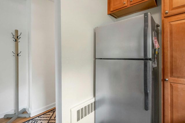 kitchen featuring freestanding refrigerator, brown cabinets, baseboards, and visible vents