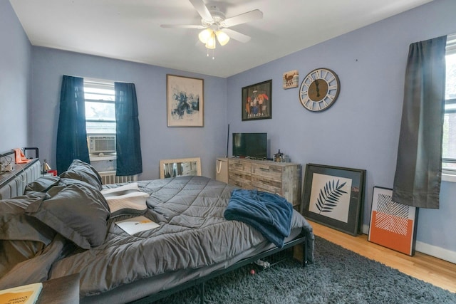 bedroom with cooling unit, wood finished floors, and a ceiling fan