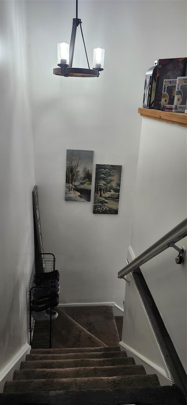 stairway featuring baseboards and carpet flooring