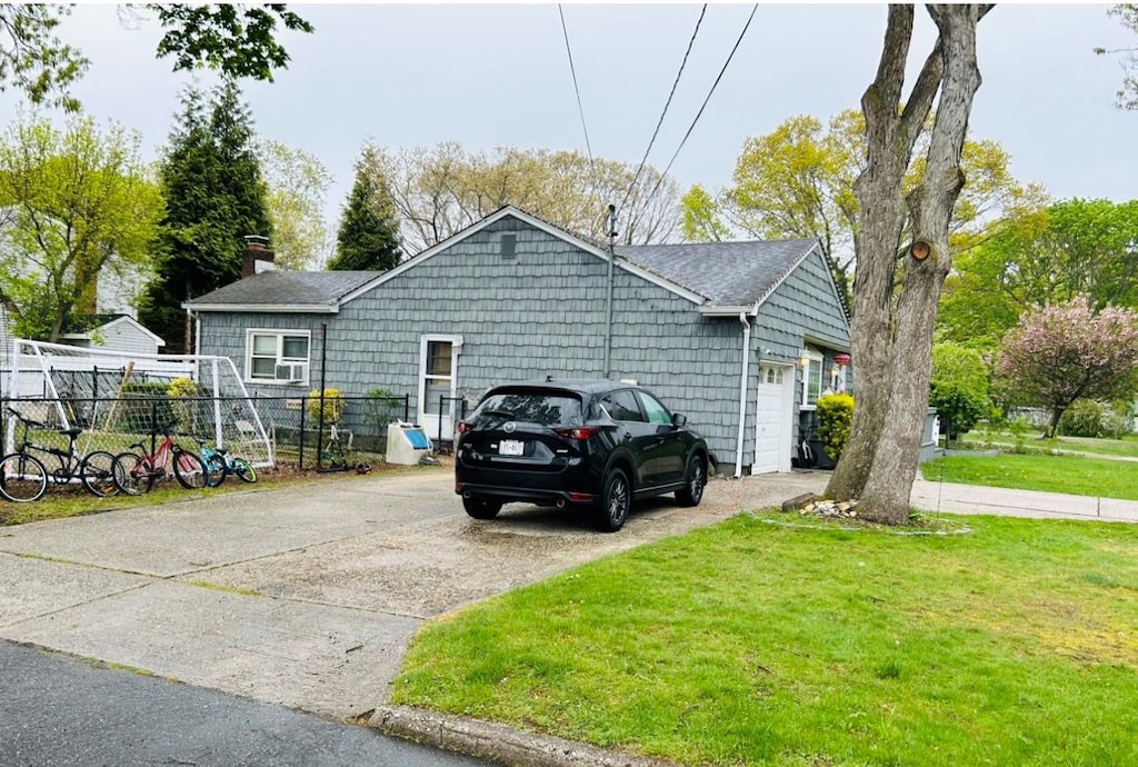 exterior space featuring fence, an attached garage, a front yard, a chimney, and driveway