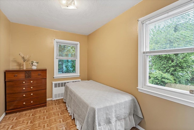 39-27 216th St, Bayside, NY 11361 - bedroom featuring radiator heating unit, multiple windows, a textured ceiling, and baseboards