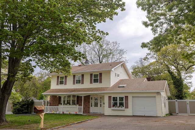 view of front of property featuring an attached garage, a gate, fence, a porch, and driveway