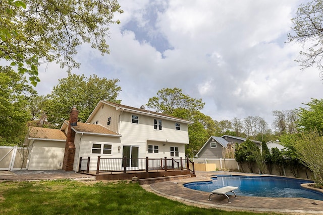 rear view of house with a chimney, a wooden deck, a fenced backyard, a yard, and a fenced in pool