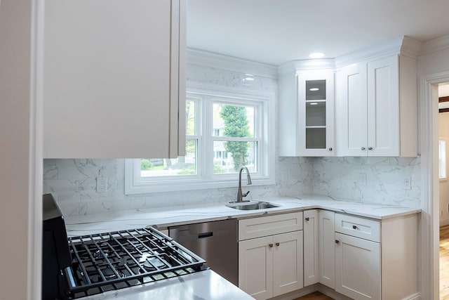 kitchen with stainless steel dishwasher, light stone countertops, white cabinetry, and a sink