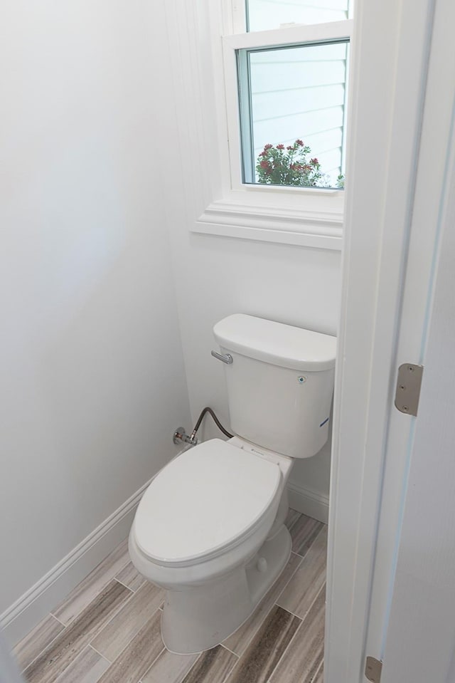 bathroom with toilet, baseboards, and wood finished floors