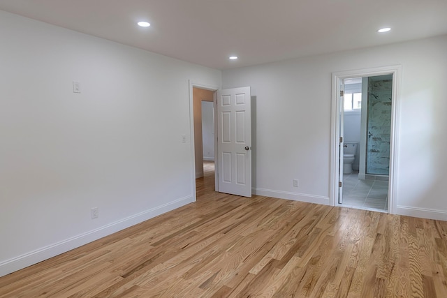 interior space with light wood finished floors, connected bathroom, baseboards, and recessed lighting