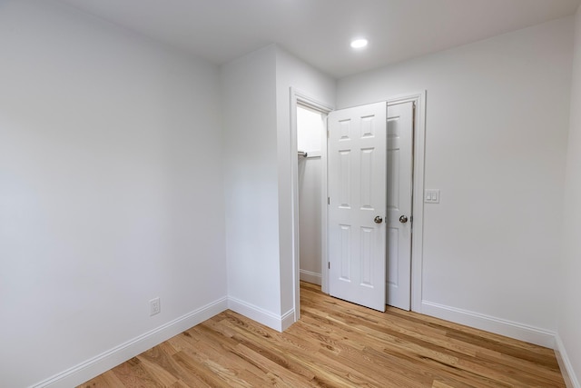 spare room featuring light wood-type flooring, baseboards, and recessed lighting