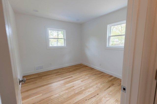 spare room with baseboards, light wood finished floors, and visible vents