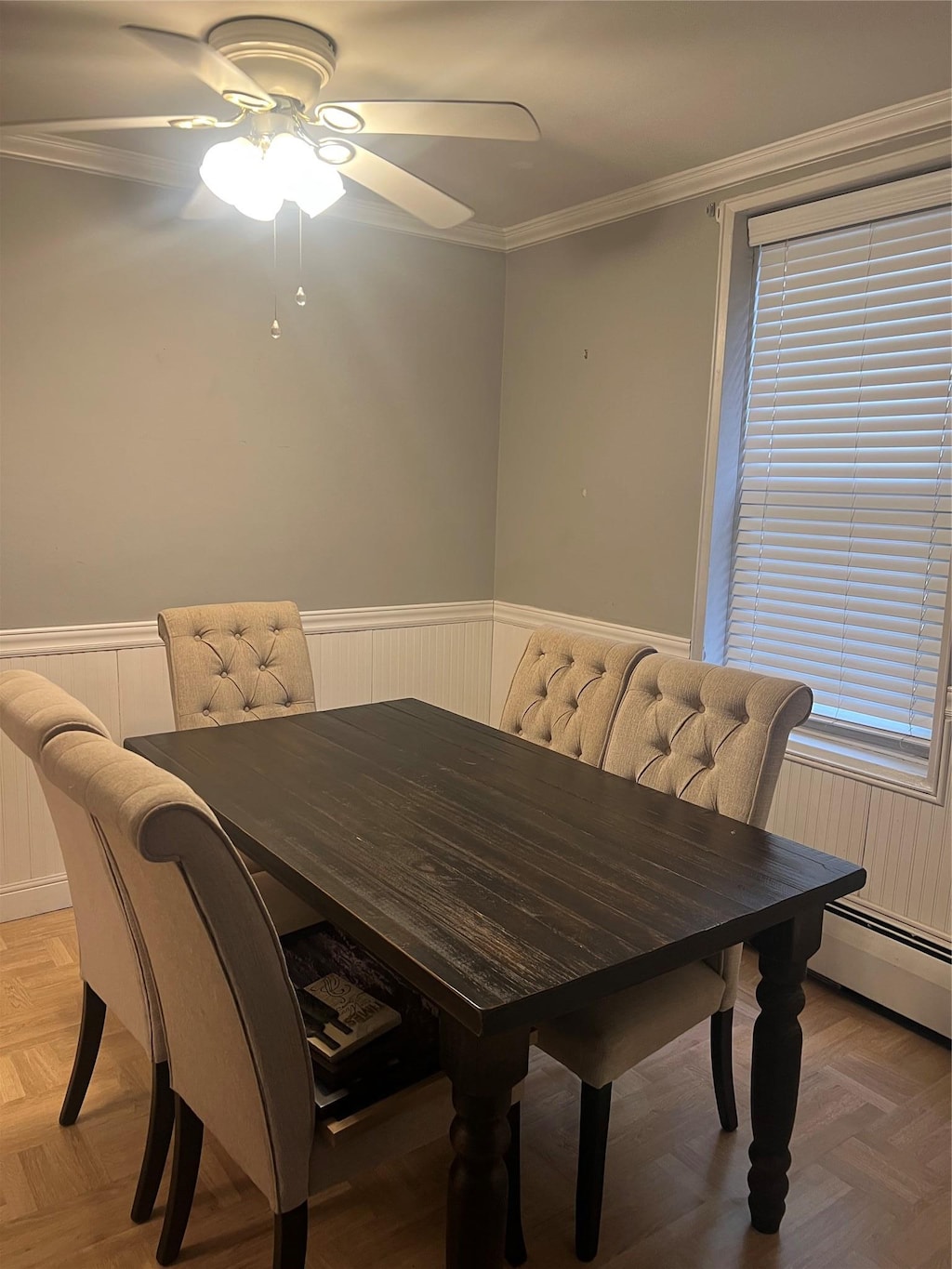 dining room featuring a ceiling fan, a wainscoted wall, crown molding, and a baseboard radiator